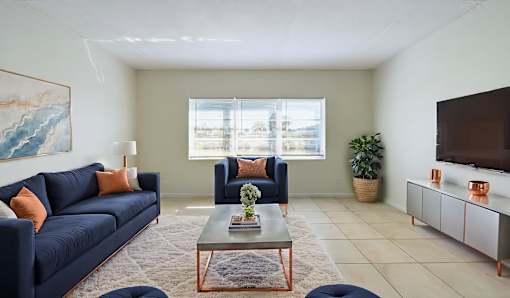 A living room with a blue couch, a coffee table, and a painting on the wall.