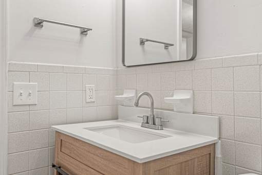 A bathroom sink with a white counter top and a wooden drawer.