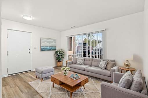 A living room with a grey couch, a coffee table, and a painting on the wall.