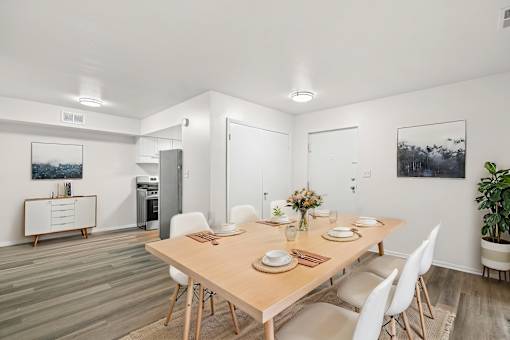 A dining room with a wooden table and white chairs.