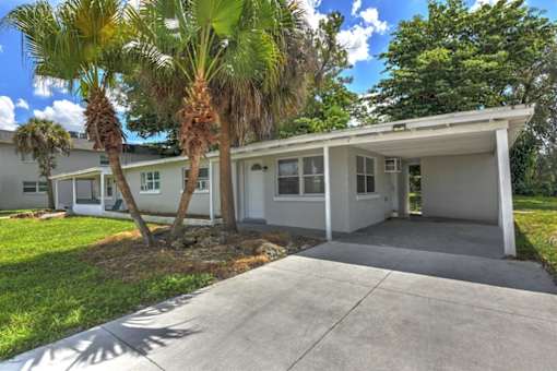 A house with a white garage door and a palm tree in front.