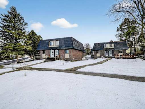 A snow-covered ground with a house and a tree in the foreground.
