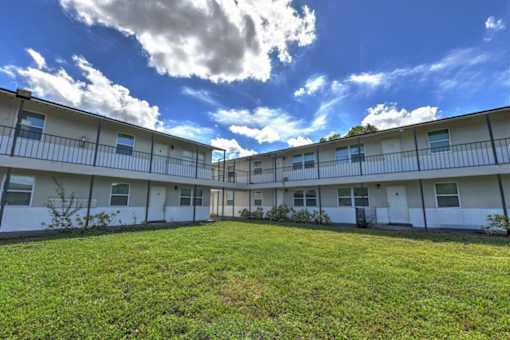 A sunny day at the apartment complex with green grass and white buildings.