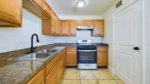 A kitchen with wooden cabinets and a stainless steel dishwasher.
