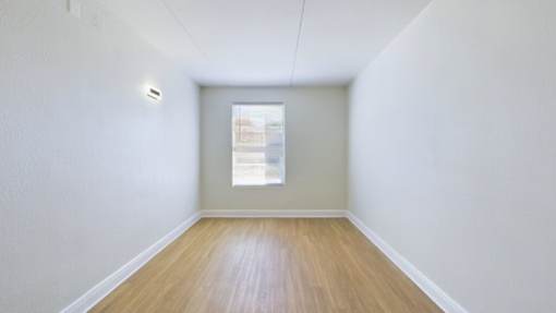A room with a window and wooden flooring.