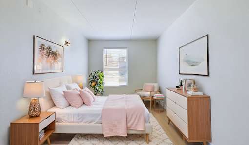 A bedroom with a bed, nightstand, and chair.
