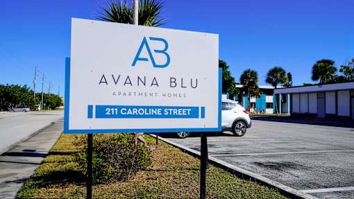 A sign for Avana Blu Apartment Homes is displayed in front of a building.