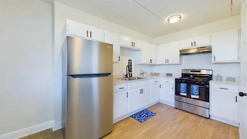 A kitchen with a stainless steel refrigerator and white cabinets.