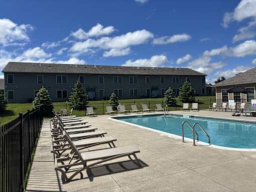 A pool with sun loungers and a building in the background.