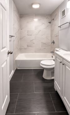 A white toilet sits in a bathroom with black tile flooring.