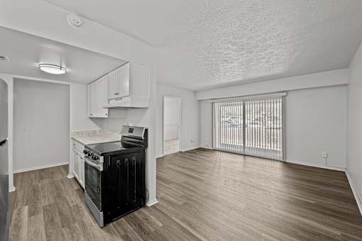 A kitchen with a black stove top oven and wooden flooring.