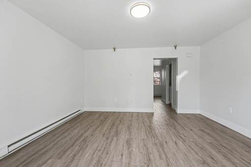 A room with wooden flooring and white walls.