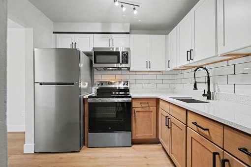 A modern kitchen with a stainless steel refrigerator, microwave, oven, and sink.