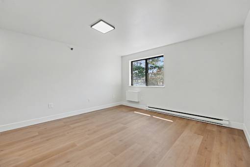 A room with a window and a wooden floor.