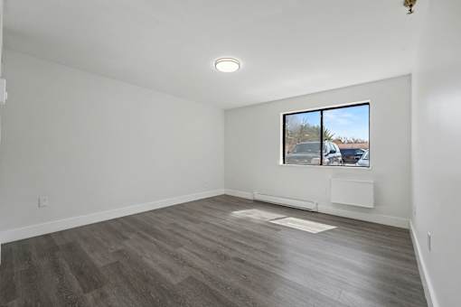 A room with a window showing a parking lot outside.