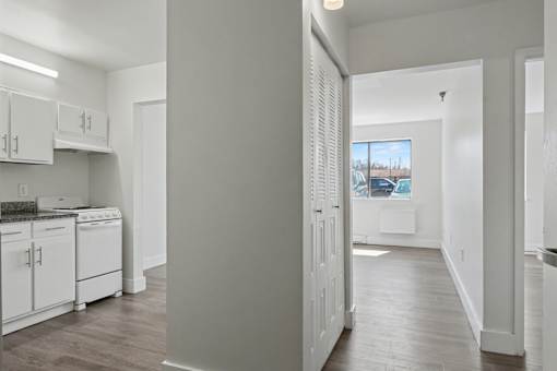 A kitchen with white cabinets and a view of a parking lot outside.