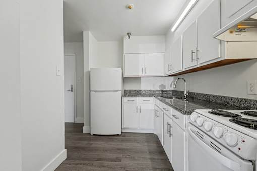 A white fridge and stove in a kitchen with white cabinets.