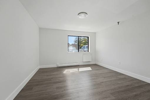 A room with a window and a wooden floor.
