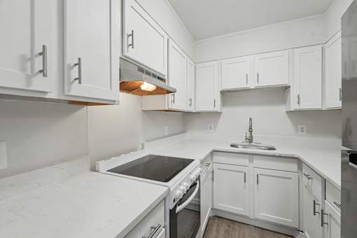 A kitchen with white cabinets and a marble countertop.