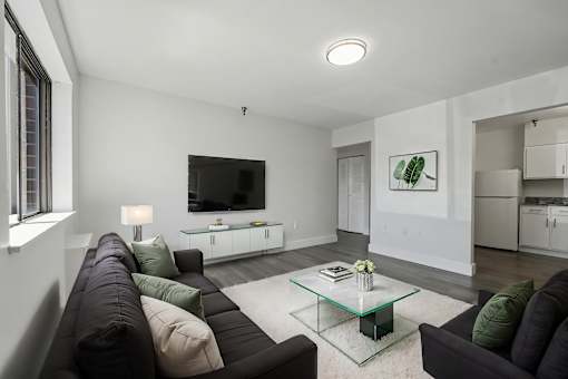 A modern living room with a black couch and a glass coffee table.