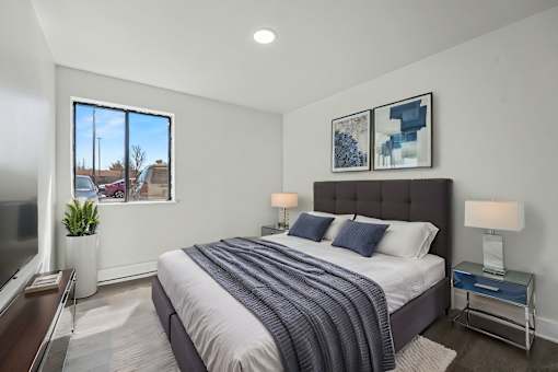 A bedroom with a large bed and a window overlooking a residential area.