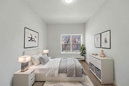 A bedroom with a bed, nightstands, and pictures on the wall.