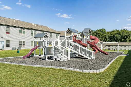 A playground with a red slide and white fence.