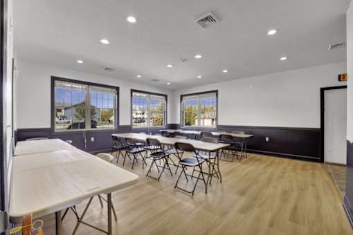 A room with tables and chairs and windows.