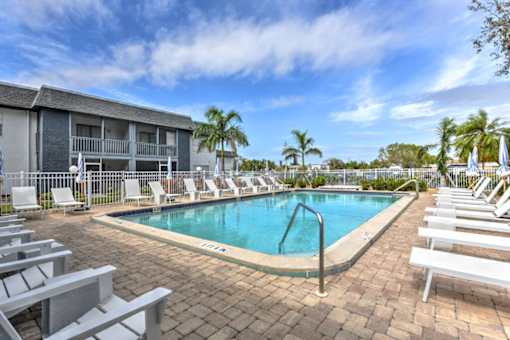 A pool surrounded by lounge chairs and palm trees.