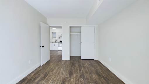 A room with white walls and wood flooring with two open doors.