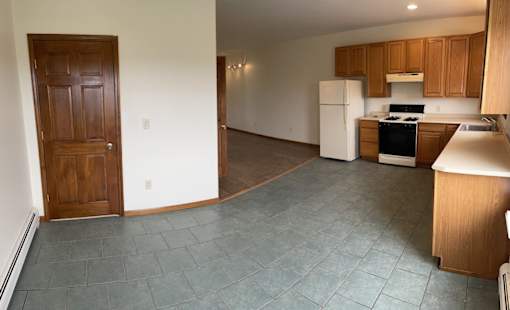 A kitchen with a white fridge and wooden cabinets.