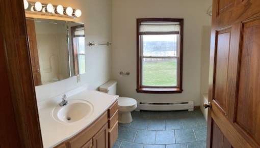 A bathroom with a sink, toilet, and window.