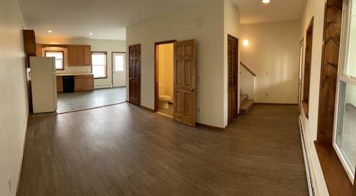 A spacious living room with wooden floors and furniture.