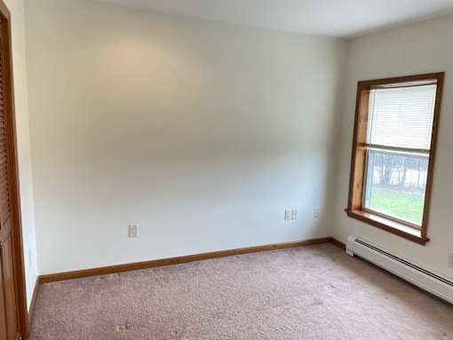 A room with a window and a carpeted floor.