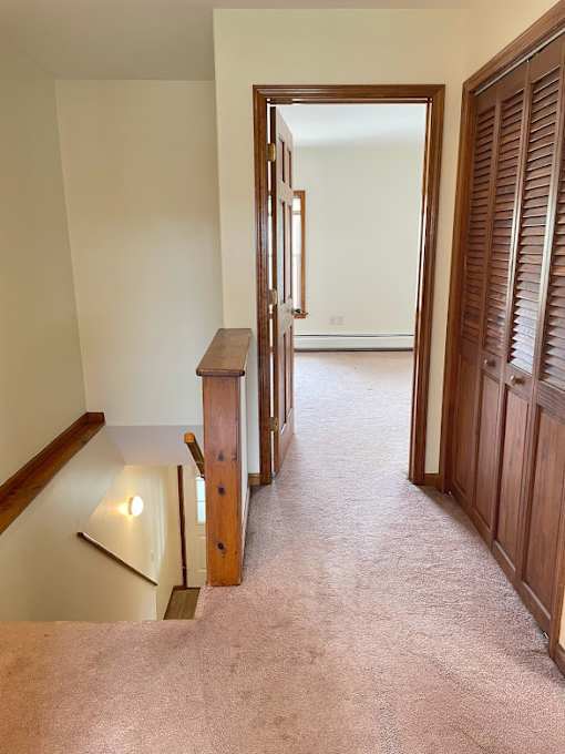 A hallway with a wooden staircase and a door on the right.