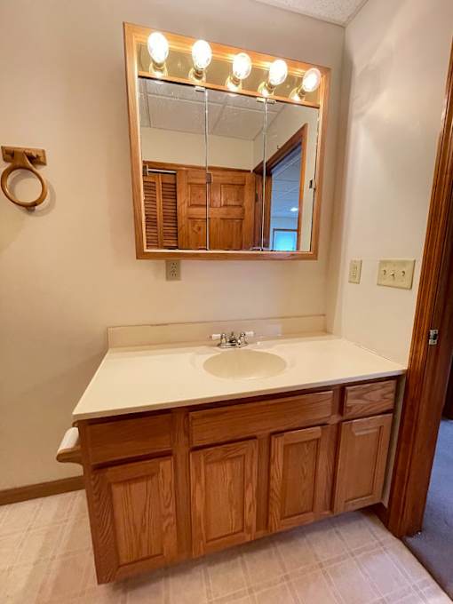A bathroom with a sink and a mirror with lights on it.