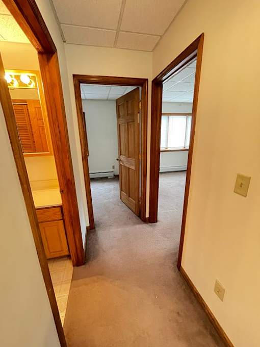 A hallway with a wooden door and a white wall.
