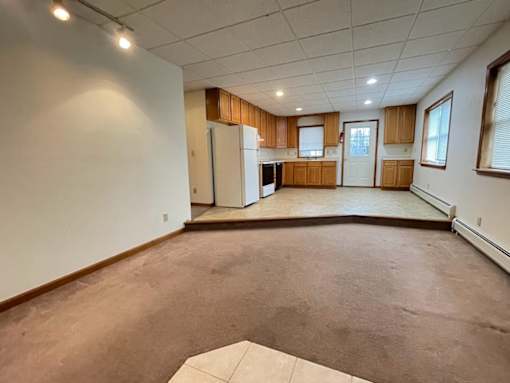 A spacious room with a kitchen area in the background.
