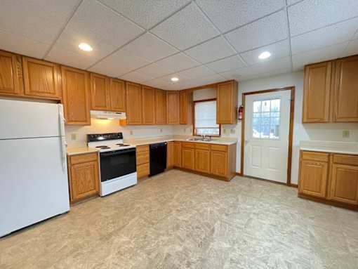 A kitchen with wooden cabinets and a white refrigerator.