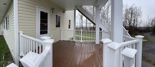 A small house with a porch and stairs leading to the second floor.