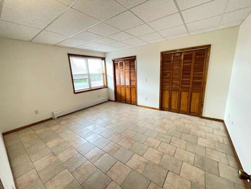 A room with a tiled floor and a window with wooden shutters.
