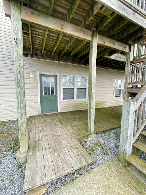 A wooden deck with a green door and windows.