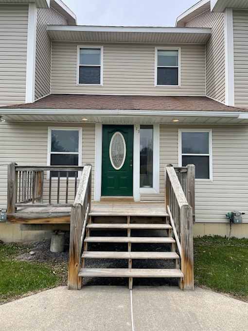 A house with a green door and a wooden staircase leading to it.