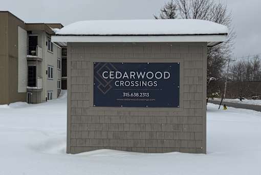 A sign for Cedarwood Crossings stands in the snow.