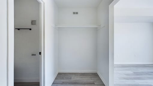A white room with a door and a small vent on the wall.
