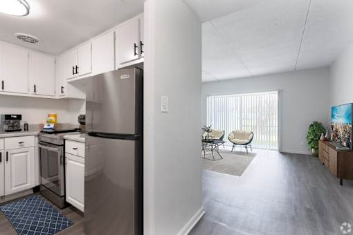A kitchen with white cabinets and a stainless steel refrigerator.
