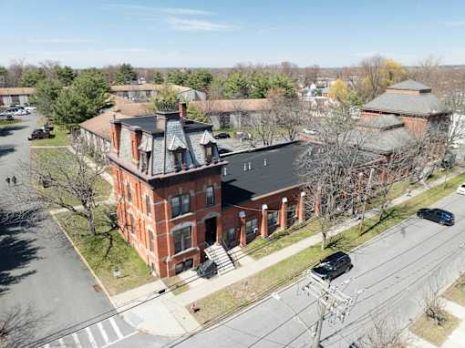 A large red brick building with a black roof and a tower with a dome on top.