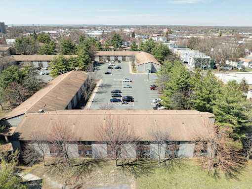 A parking lot is in front of a building with a brown roof.
