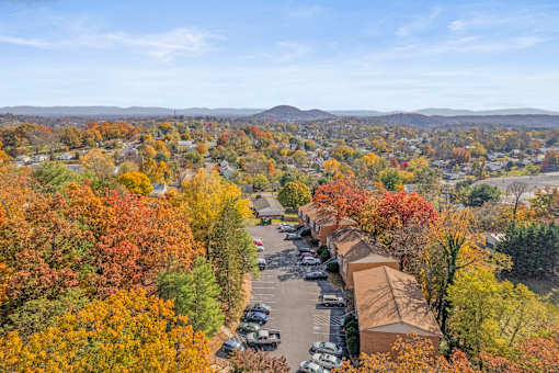 A view of a residential area with a parking lot and houses surrounded by trees with autumn foliage.