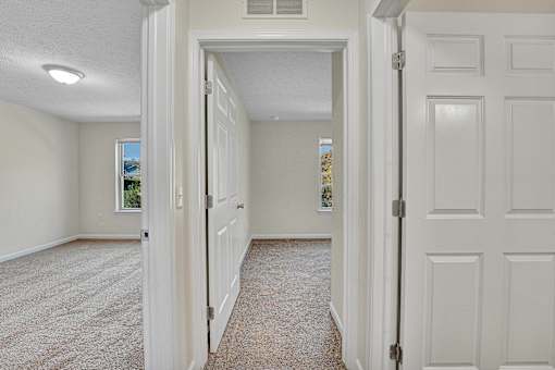 A white door is open to a hallway with a carpeted floor.